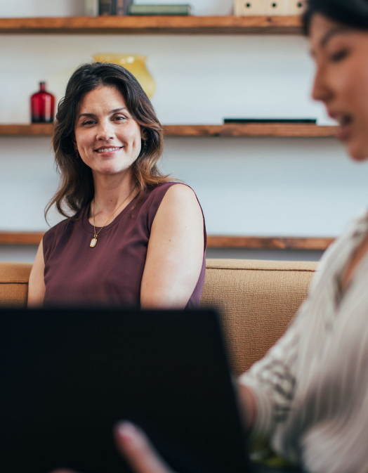 A woman presenting on a computer screen to another woman 