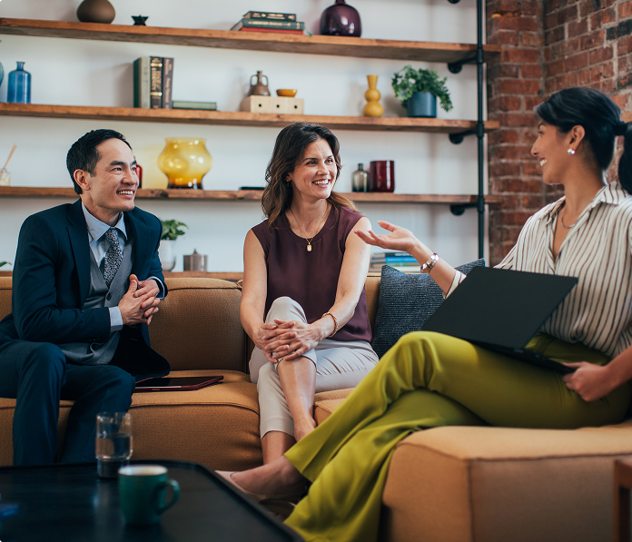 A man and two women sitting on a couch and having a discussion